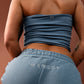 Rear view of a person wearing a dusty blue strapless tube top and matching sweatpants with 'MARGOT' embroidered on the back pocket, against a warm brown background.